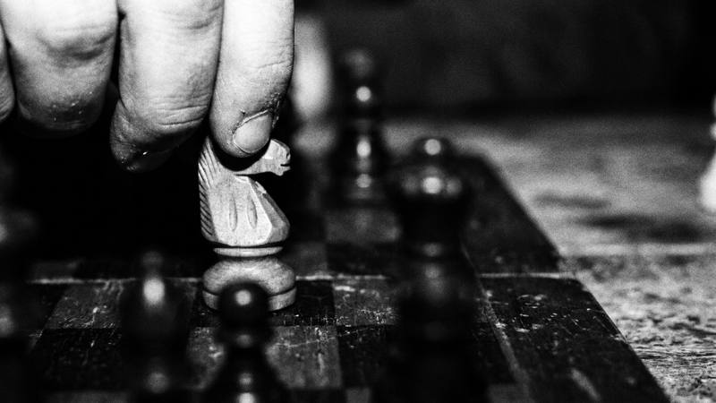 Fingers lifting a knight off the board
